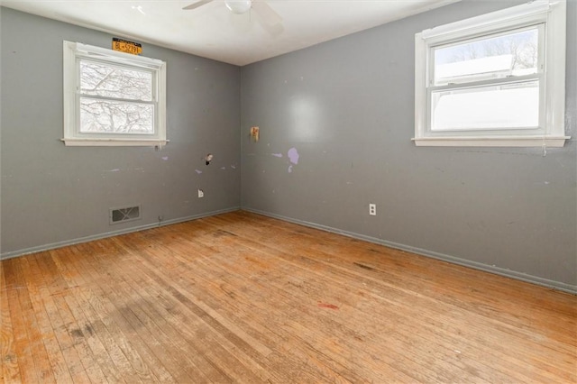 unfurnished room featuring a ceiling fan, visible vents, light wood-style flooring, and baseboards