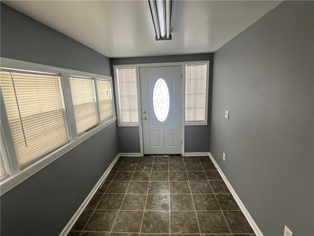 foyer entrance featuring dark tile patterned flooring and baseboards