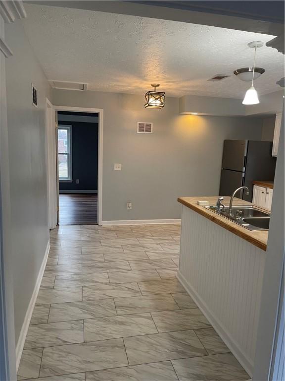 kitchen with freestanding refrigerator, marble finish floor, visible vents, and hanging light fixtures