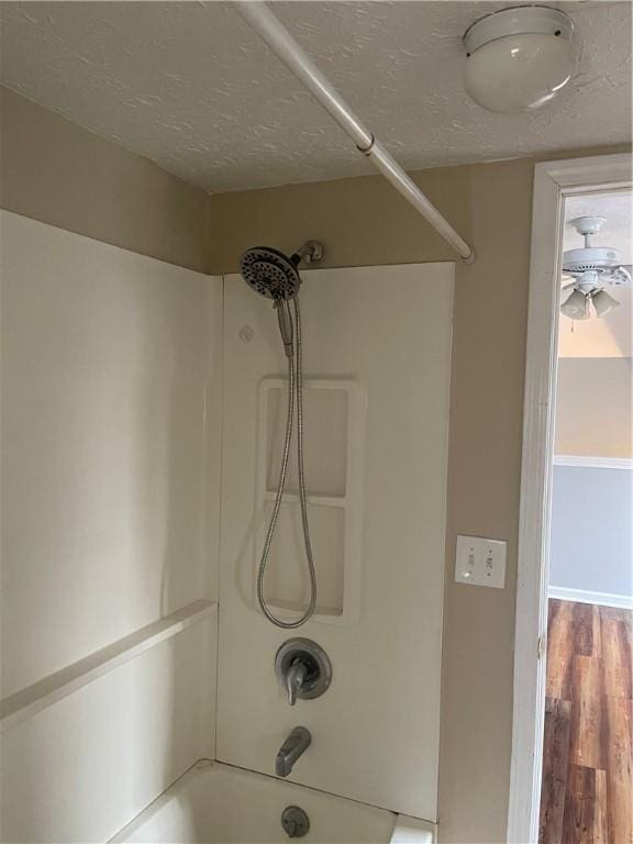 room details featuring shower / bath combination, a textured ceiling, and wood finished floors