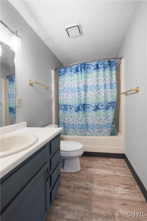 bathroom featuring toilet, wood finished floors, vanity, and shower / tub combo with curtain