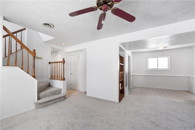 interior space featuring light colored carpet, visible vents, stairway, and baseboards