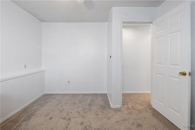 spare room featuring light carpet and baseboards