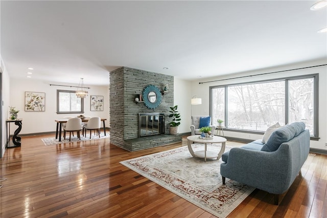 living area featuring recessed lighting, a fireplace, wood finished floors, and baseboards