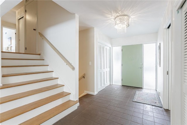 foyer entrance with a notable chandelier, stairway, and baseboards