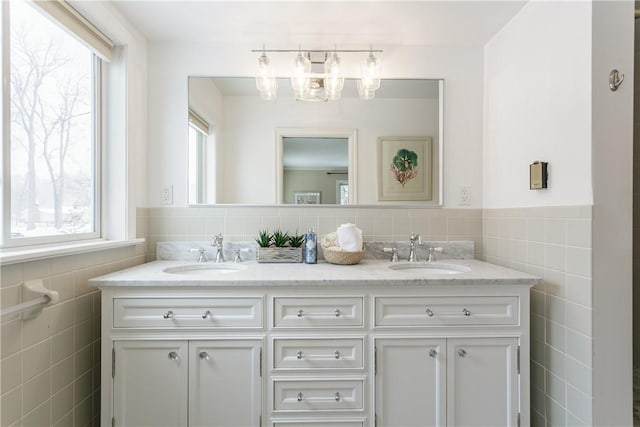 full bathroom featuring a sink, tile walls, and double vanity