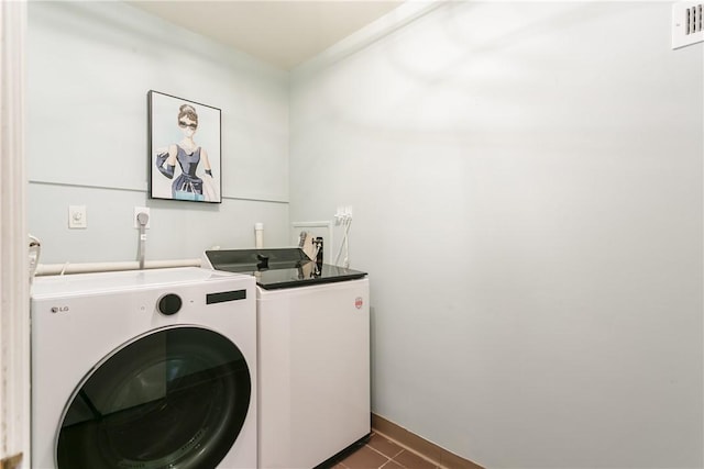 washroom featuring laundry area, dark tile patterned floors, washing machine and dryer, and visible vents