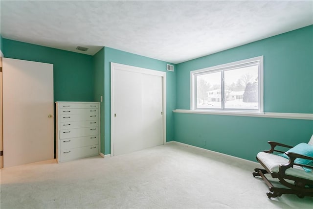 living area featuring carpet, visible vents, a textured ceiling, and baseboards