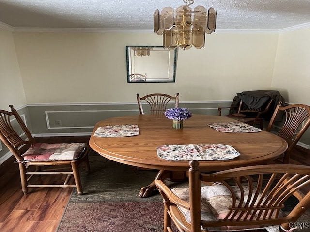 dining room with crown molding, a notable chandelier, a textured ceiling, and wood finished floors