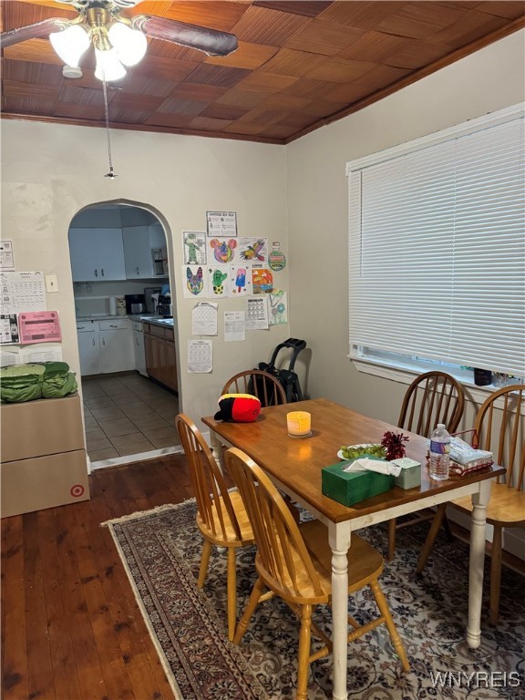 dining area featuring arched walkways, dark wood-style flooring, and ceiling fan