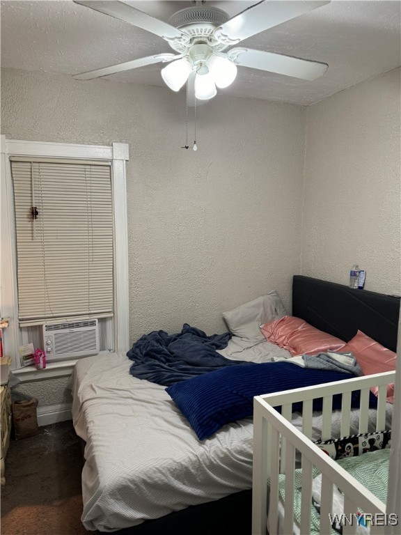 bedroom with cooling unit, a textured wall, and ceiling fan