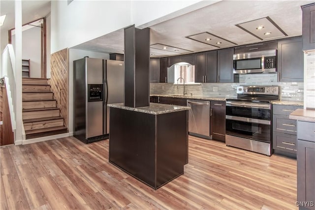 32702 Old Town Springs Rd, Clayton, NY 13622 - kitchen featuring light stone counters, a sink, tasteful backsplash, appliances with stainless steel finishes, and light wood-style flooring