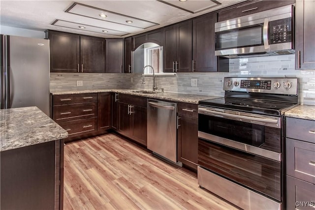 32702 Old Town Springs Rd, Clayton, NY 13622 - kitchen featuring light stone counters, a sink, appliances with stainless steel finishes, light wood-style flooring, and dark brown cabinets