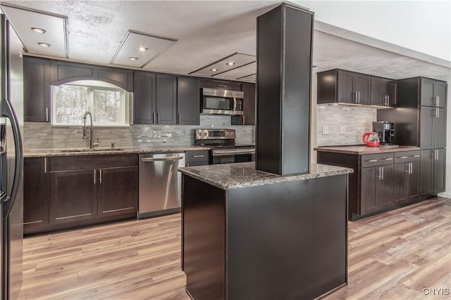32702 Old Town Springs Rd, Clayton, NY 13622 - kitchen featuring backsplash, a sink, light wood-style floors, stone countertops, and appliances with stainless steel finishes