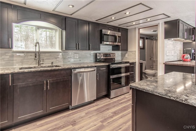 32702 Old Town Springs Rd, Clayton, NY 13622 - kitchen with stainless steel appliances, dark stone counters, backsplash, a sink, and light wood finished floors