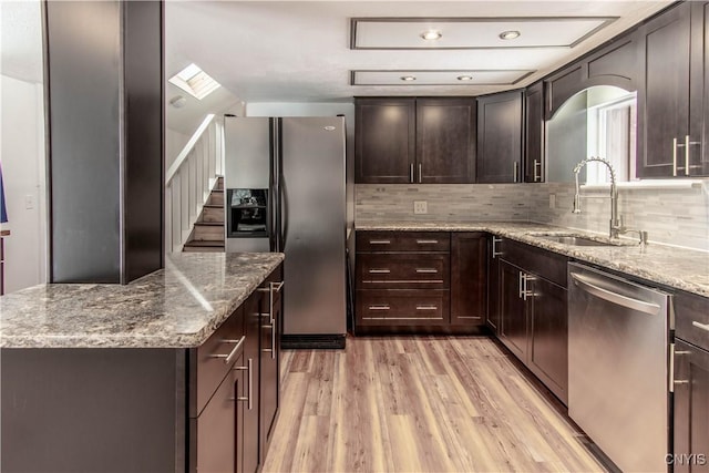 32702 Old Town Springs Rd, Clayton, NY 13622 - kitchen with tasteful backsplash, stainless steel appliances, a sink, light wood-style flooring, and light stone countertops