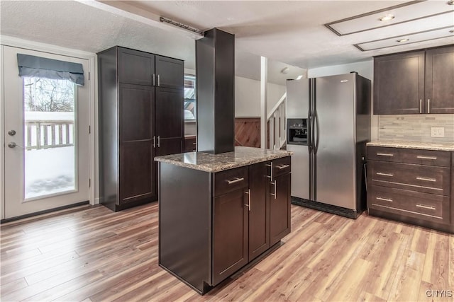 32702 Old Town Springs Rd, Clayton, NY 13622 - kitchen with backsplash, a kitchen island, light stone countertops, stainless steel fridge, and light wood-type flooring