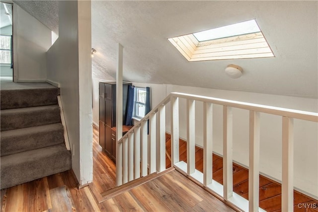 32702 Old Town Springs Rd, Clayton, NY 13622 - stairway with a textured ceiling, vaulted ceiling with skylight, and wood finished floors