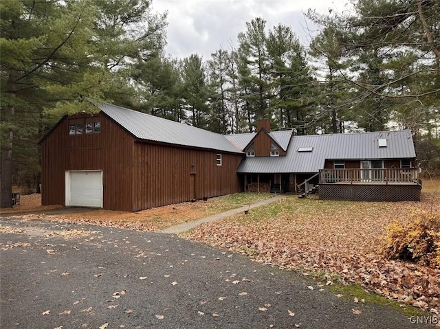 32702 Old Town Springs Rd, Clayton, NY 13622 - view of front of house featuring aphalt driveway, a garage, metal roof, and a wooden deck