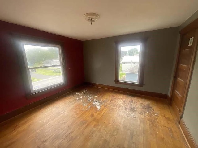 unfurnished room featuring light wood finished floors, a healthy amount of sunlight, and baseboards