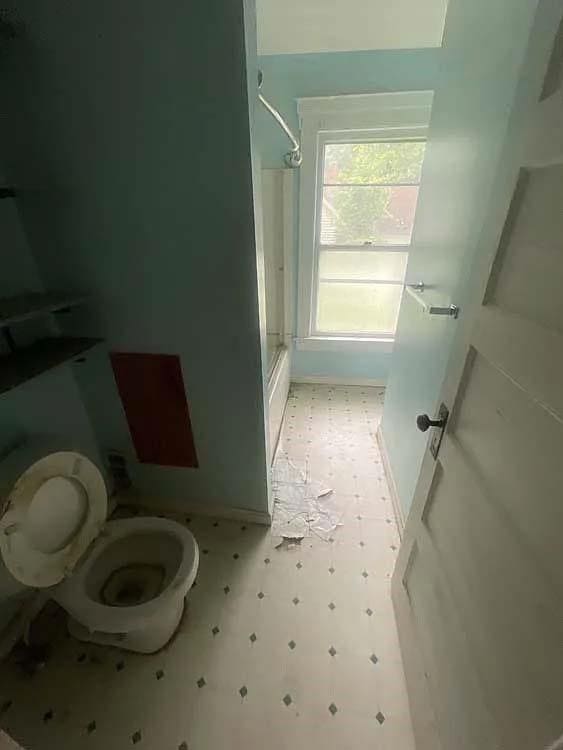 bathroom with bath / shower combo with glass door, toilet, and tile patterned floors