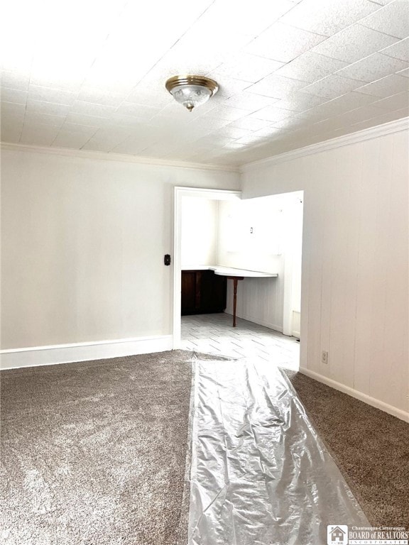 spare room with ornamental molding, carpet flooring, and baseboards