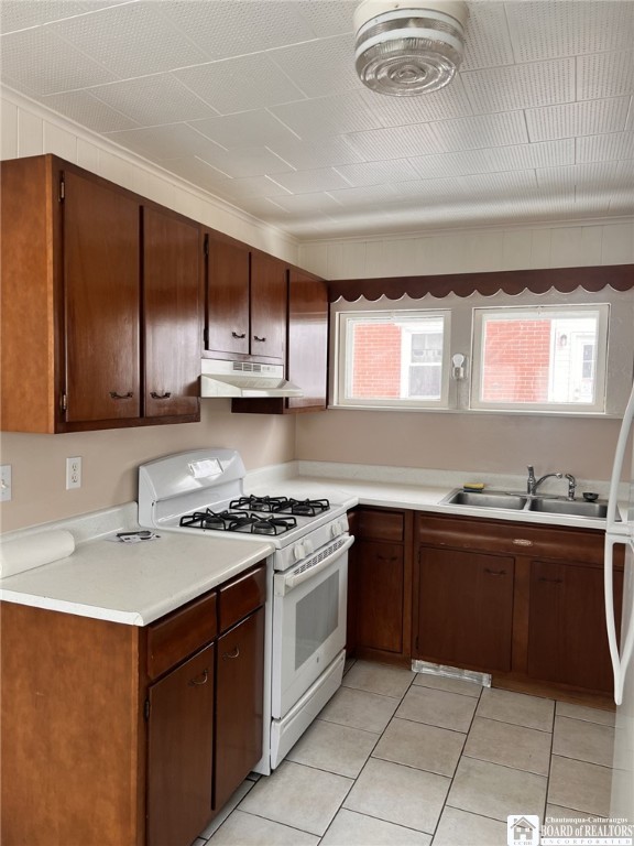 kitchen with under cabinet range hood, a wealth of natural light, light countertops, and gas range gas stove