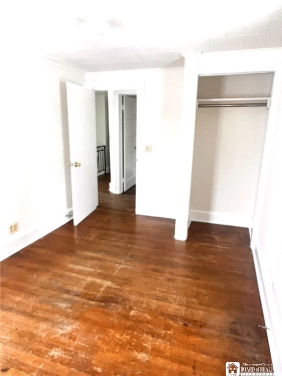unfurnished bedroom featuring dark wood-style flooring and a closet