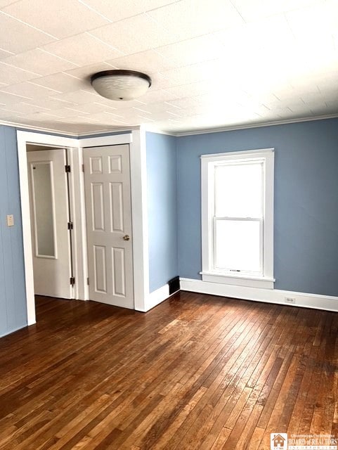 unfurnished room featuring baseboards and dark wood finished floors