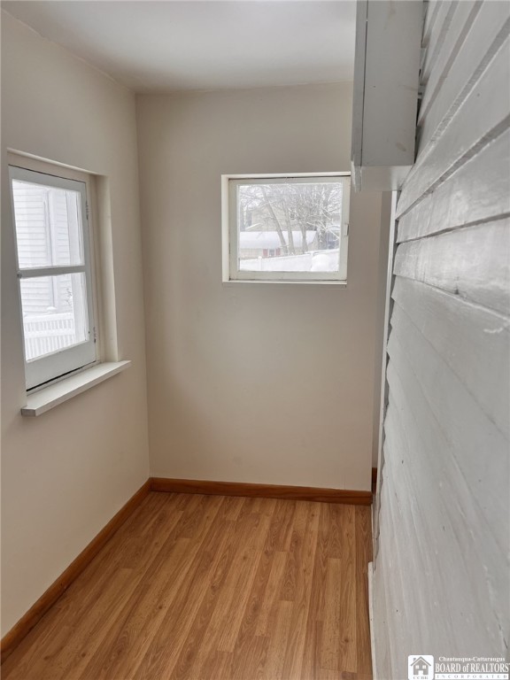 spare room featuring baseboards and light wood finished floors