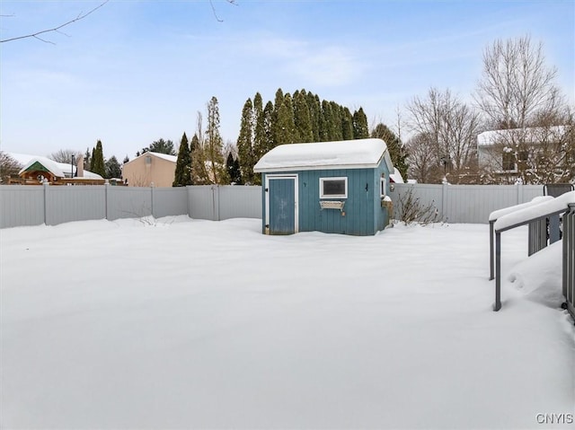 yard layered in snow featuring an outdoor structure and a fenced backyard