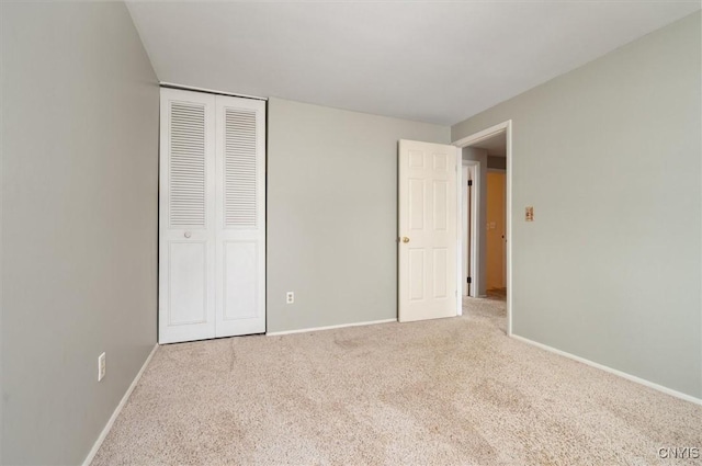 unfurnished bedroom with carpet, a closet, and baseboards