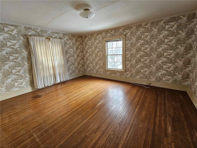 spare room featuring wood finished floors, baseboards, and wallpapered walls