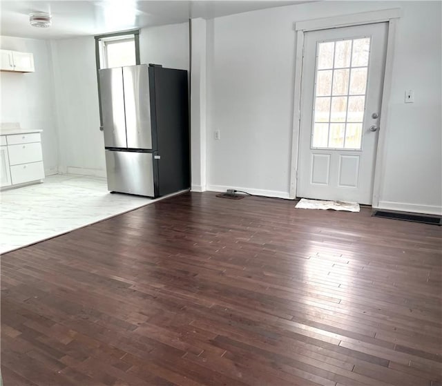 kitchen with dark wood-style floors, freestanding refrigerator, a healthy amount of sunlight, and white cabinets