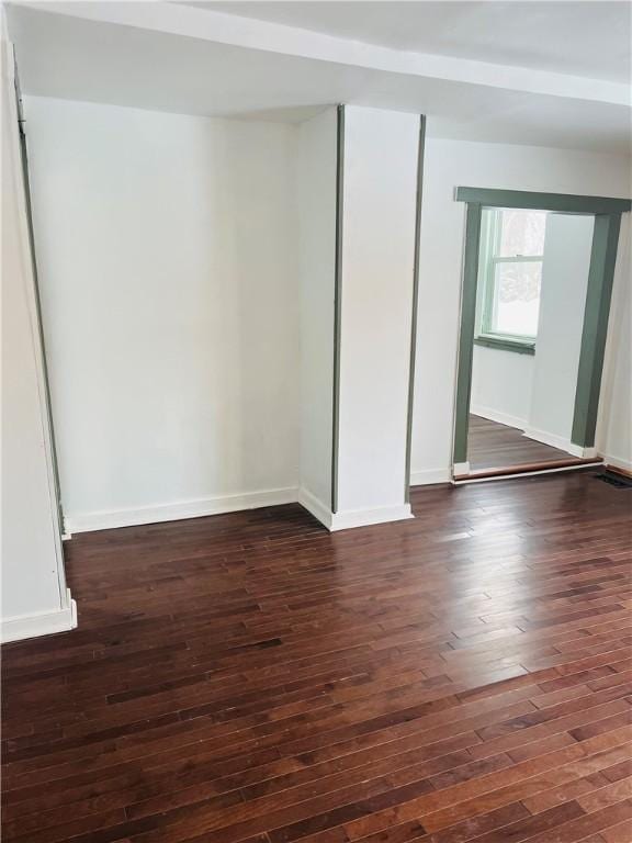 spare room featuring dark wood-style floors and baseboards