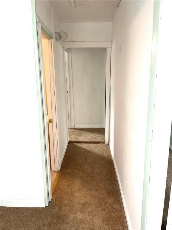 hall with baseboards and dark colored carpet