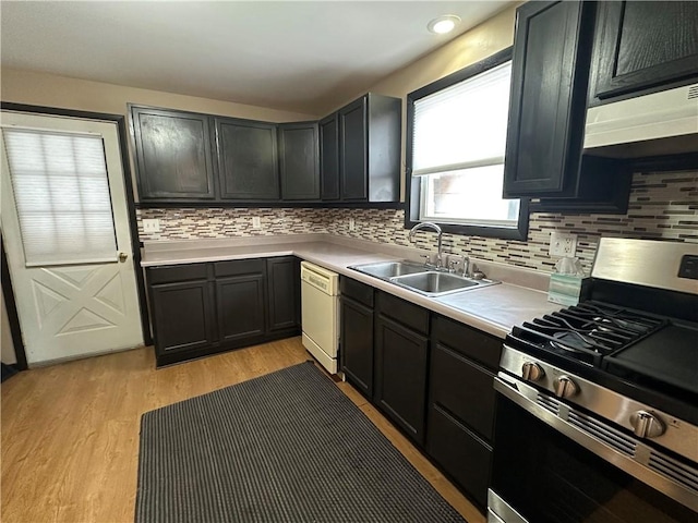 kitchen featuring light wood finished floors, stainless steel gas range oven, white dishwasher, light countertops, and a sink