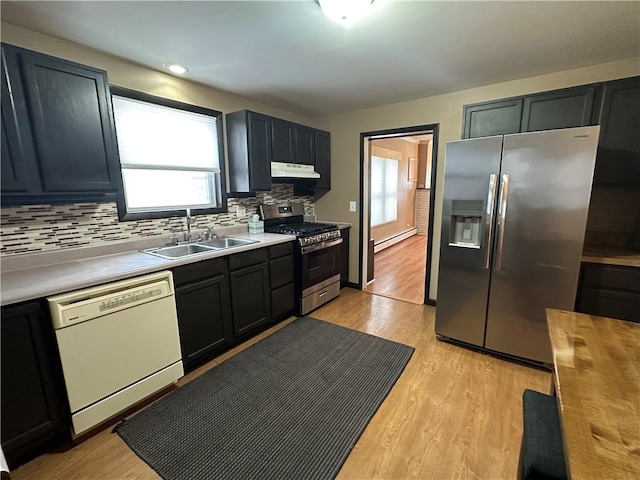 kitchen with a baseboard radiator, light wood-style flooring, stainless steel appliances, under cabinet range hood, and a sink