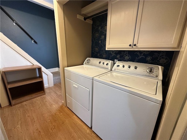 laundry area with light wood-type flooring, cabinet space, and washer and clothes dryer