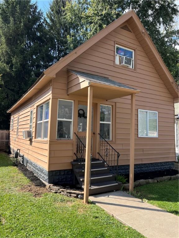 bungalow featuring fence, cooling unit, and a front yard