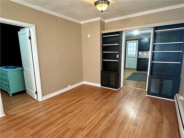 empty room featuring ornamental molding, baseboard heating, wood finished floors, and baseboards