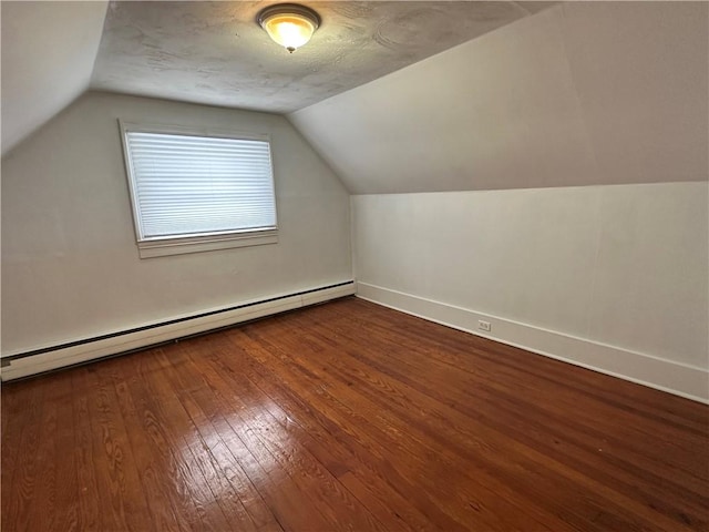 additional living space with a baseboard radiator, vaulted ceiling, baseboards, and wood finished floors