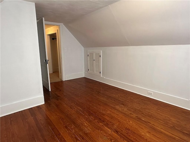 bonus room with dark wood-type flooring, lofted ceiling, and baseboards