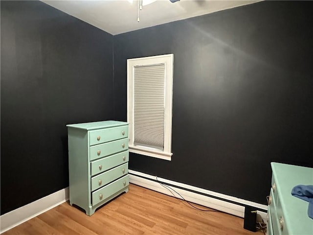 bedroom featuring light wood-type flooring, baseboards, and a baseboard radiator