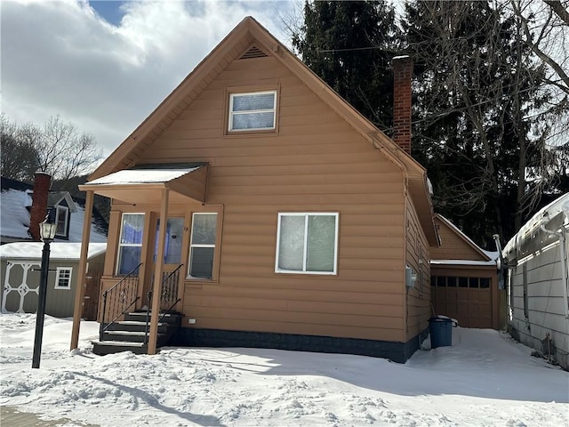 snow covered rear of property with a chimney