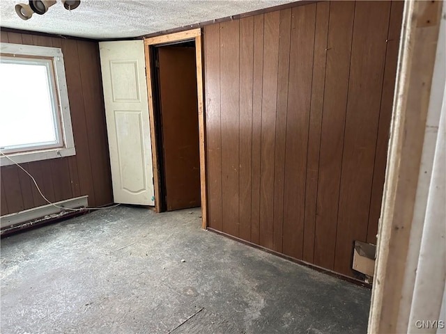 unfurnished bedroom featuring a textured ceiling and wooden walls