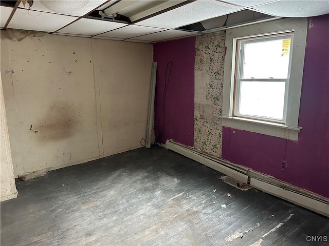 unfurnished room with dark wood-type flooring, a drop ceiling, and baseboard heating