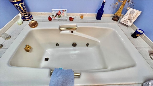 interior details featuring a jetted tub and a sink