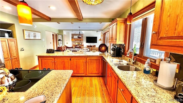 kitchen featuring light stone counters, hanging light fixtures, a sink, stovetop, and a peninsula