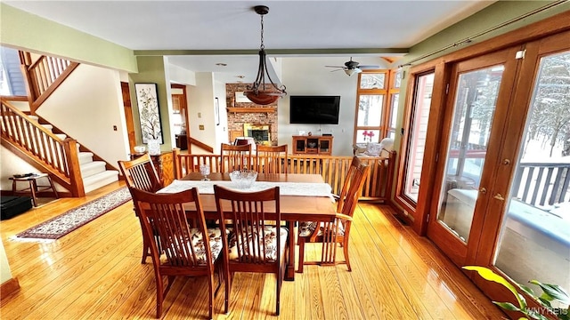 dining space featuring stairway, a fireplace, and light wood-style flooring